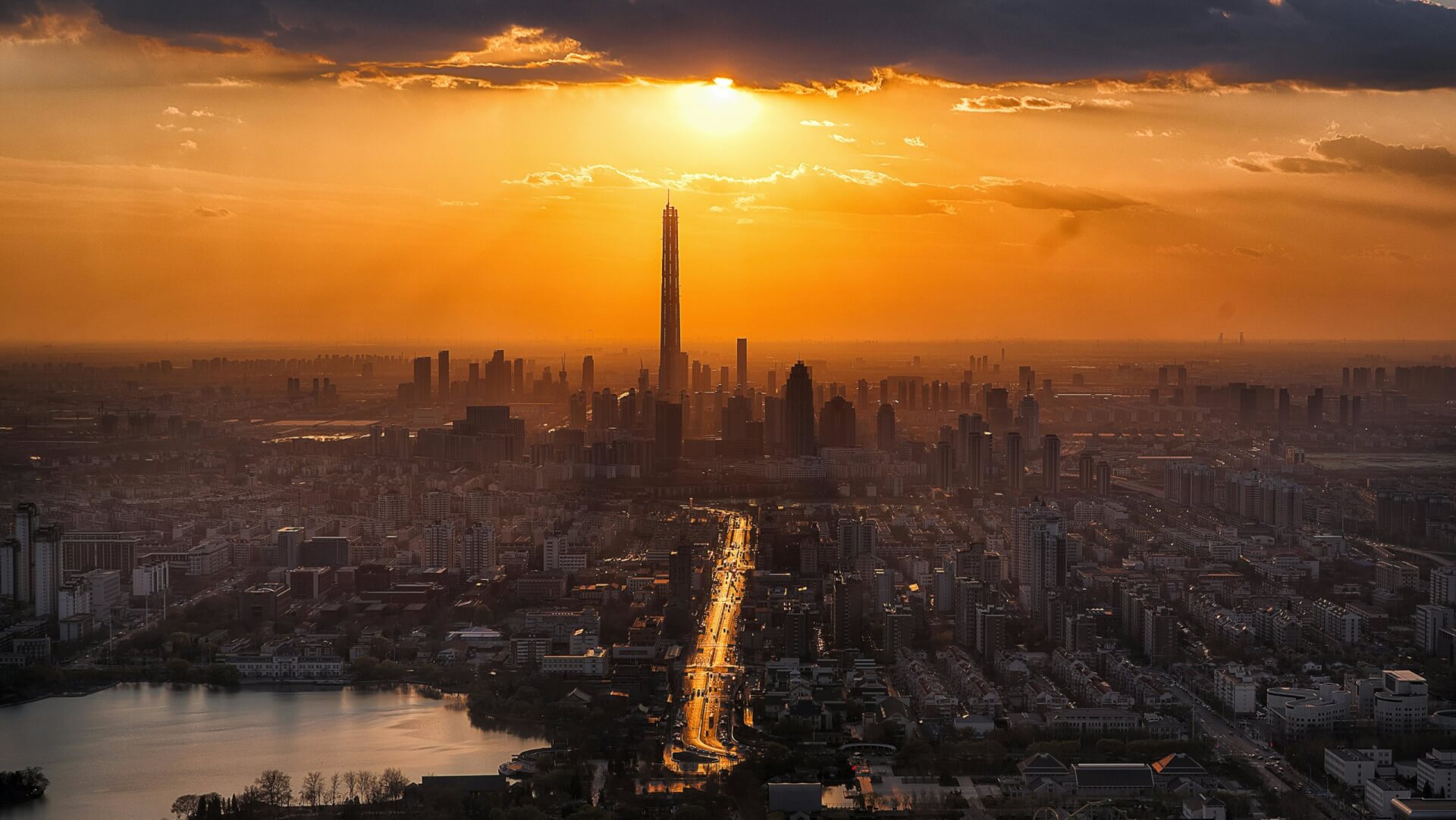Photo d'un ciel avec un coucher de soleil orangé au dessus d'une ville avec des grattes-ciel